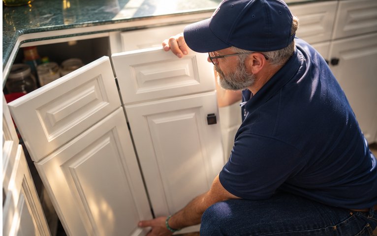 Geoff Hainer tightening and refreshing kitchen cabinets